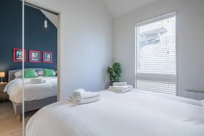 a bedroom with a large white bed and a mirror at Superb Central Apt With Parking in Cambridge