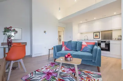 a living room with a blue couch and a kitchen at Superb Central Apt With Parking in Cambridge