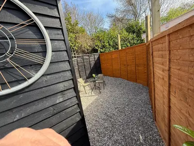 a wooden fence with a table and chairs next to it at Colne cabin in Earls Colne