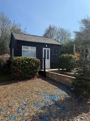a small black house with a white door at Colne cabin in Earls Colne