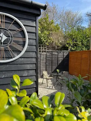 a patio with a clock on the side of a house at Colne cabin in Earls Colne