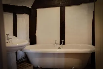 a bathroom with a white tub and a sink at Willow Cottage in Saxtead