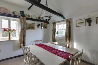 a dining room with a white table and chairs at Willow Cottage in Saxtead