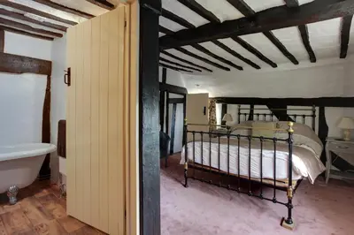 a bedroom with a bed and a tub in a room at Willow Cottage in Saxtead