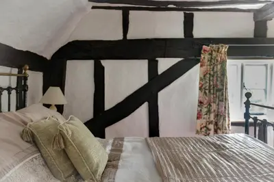 a bedroom with a large bed with a wooden headboard at Willow Cottage in Saxtead