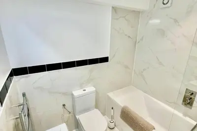 a white bathroom with a toilet and a bath tub at 3 Bed Flat - Sleeps 6 - Parking - Wifi in Cambridge