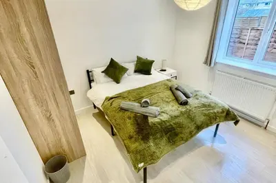 a bedroom with a bed with a green blanket at 3 Bed Flat - Sleeps 6 - Parking - Wifi in Cambridge