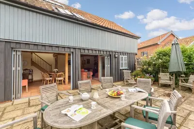 a patio with a wooden table and chairs at The Granary, Hacheston 4 in Marlesford