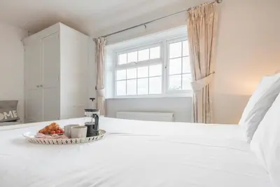 a white bed with a basket of fruit on it at Milestone House, Aldeburgh in Aldeburgh
