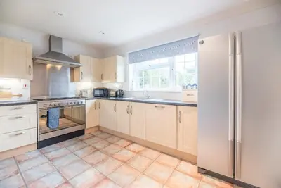 a kitchen with wooden cabinets and a stainless steel refrigerator at Milestone House, Aldeburgh in Aldeburgh