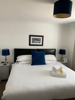 a bedroom with a large white bed with a blue pillow at Tirah Guest House in Aldeburgh