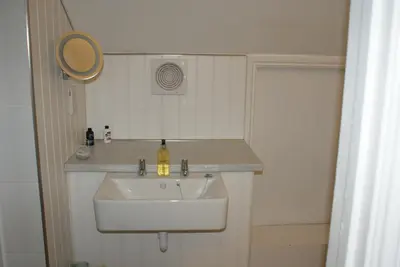 a bathroom with a white sink and a mirror at Tirah Guest House in Aldeburgh