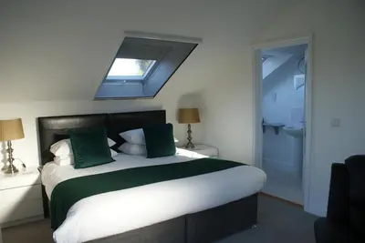 a bedroom with a large bed with green pillows at Tirah Guest House in Aldeburgh