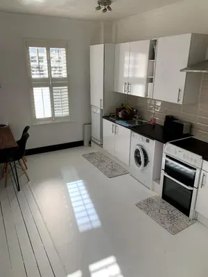 a kitchen with white cabinets and a washer and dryer at Charming 2-Bedroom Maisonette in Leigh-on-Sea