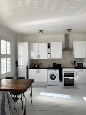 a kitchen with white appliances and a wooden table at Charming 2-Bedroom Maisonette in Leigh-on-Sea