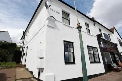 a white building with a green pole in front of it at Charming 2-Bedroom Maisonette in Leigh-on-Sea