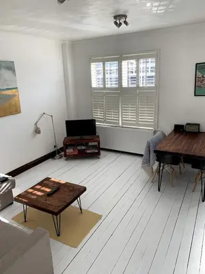 a living room with a table and a piano at Charming 2-Bedroom Maisonette in Leigh-on-Sea