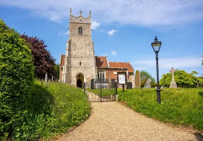 an old church with a gate and a street light at The Shepherds Hut at Anvil House in Woodbridge