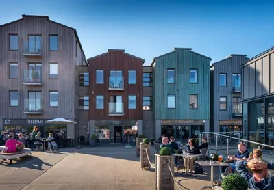 a group of people sitting at tables in front of buildings at The Shepherds Hut at Anvil House in Woodbridge
