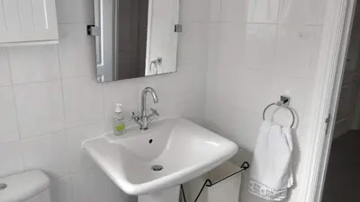a white bathroom with a sink and a mirror at Brandeston Close in Great Waldingfield