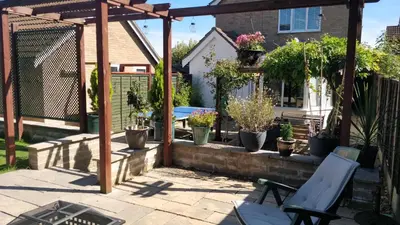 a patio with a pergola and potted plants at Brandeston Close in Great Waldingfield