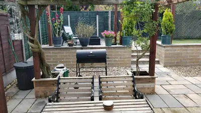 a garden with a pergola with potted plants at Brandeston Close in Great Waldingfield