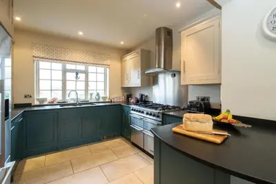 a kitchen with green cabinets and a counter top at 3 The Coastguards, Thorpeness - Only a stones throw from the Beach and very close to famous boating Meare, Country Club and Golf Club - Aldeburgh Coastal Cottages in Thorpeness