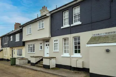 a white house with a black roof at 3 The Coastguards, Thorpeness - Only a stones throw from the Beach and very close to famous boating Meare, Country Club and Golf Club - Aldeburgh Coastal Cottages in Thorpeness