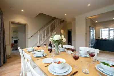 a dining room table with white dishes and wine glasses at 3 The Coastguards, Thorpeness - Only a stones throw from the Beach and very close to famous boating Meare, Country Club and Golf Club - Aldeburgh Coastal Cottages in Thorpeness