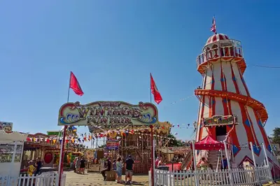a carnival with a ferris wheel and a sign at Adventure Van 6 berth St Osyth Beach Park in Saint Osyth