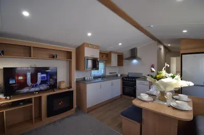 a large kitchen with a table and a television at 25 Poplars Way Walton on Naze in Walton-on-the-Naze
