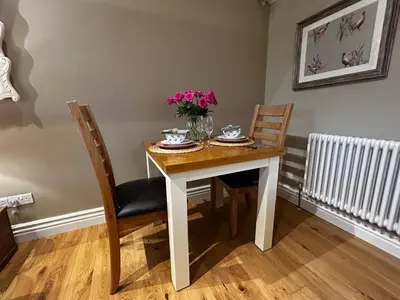 a dining room table with a vase of flowers on it at The Gate Lodge - Pet Free - Near Finchingfield & Saffron Walden in Great Sampford