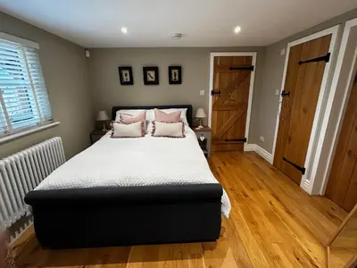 a bedroom with a large bed and a wooden floor at The Gate Lodge - Pet Free - Near Finchingfield & Saffron Walden in Great Sampford