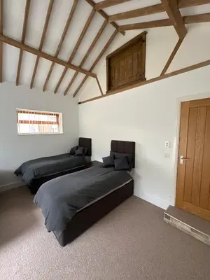 a bedroom with two beds and a wooden ceiling at character filled barn renovation in Old Hurst