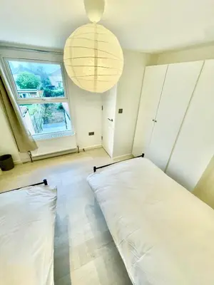 two beds in a room with a window and a chandelier at 2 Bed Flat - Sleeps 5 - Parking - Wifi in Cambridge