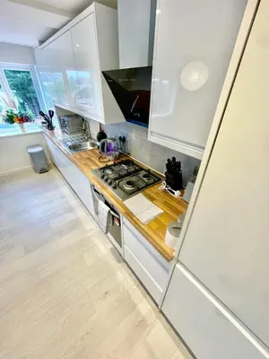 a kitchen with white cabinets and a wooden counter top at 2 Bed Flat - Sleeps 5 - Parking - Wifi in Cambridge
