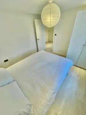 a bedroom with a large white bed with a chandelier at 2 Bed Flat - Sleeps 5 - Parking - Wifi in Cambridge