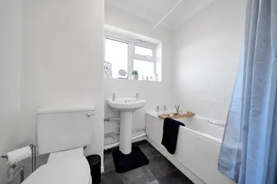 a white bathroom with a sink and a toilet and a tub at Chic Colchester Flat in Colchester