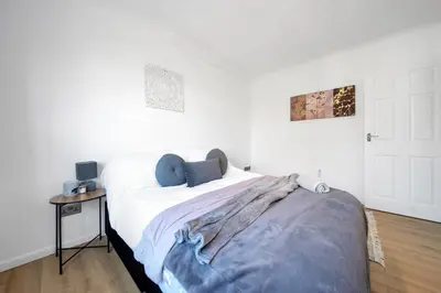 a white bedroom with a bed and a table at Chic Colchester Flat in Colchester