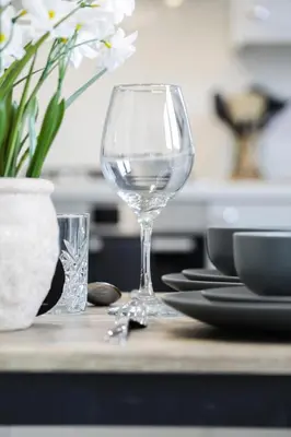 a wine glass sitting on top of a table with plates at Suffolk 3-BR Coastal House Aldeburgh & Thorpeness in Aldringham