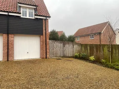 a house with two garage doors and a fence at Suffolk 3-BR Coastal House Aldeburgh & Thorpeness in Aldringham