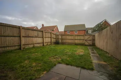 a backyard with a wooden fence and a grass yard at Suffolk 3-BR Coastal House Aldeburgh & Thorpeness in Aldringham