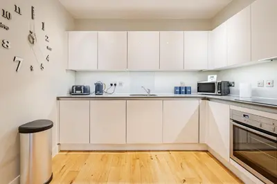 a white kitchen with white cabinets and appliances at Lovely Central Brentwood Flat in Brentwood