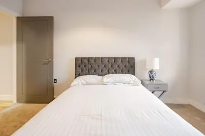a bedroom with a large white bed with a headboard at Lovely Central Brentwood Flat in Brentwood