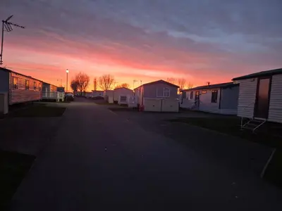 an empty street with houses and a sunset in the background at 3 Bedroom 2 Bathroom Caravan Charlie Delta in Saint Osyth