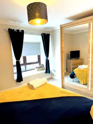 a bedroom with a mirror and a bed and a television at Modern House Soham Town Centre in Soham