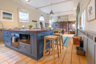 an open kitchen with a blue island and wooden floors at Belchamp Hall Stables in Belchamp Otten