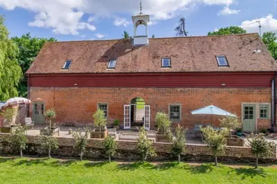 a large red brick building with a clock tower at Belchamp Hall Stables in Belchamp Otten