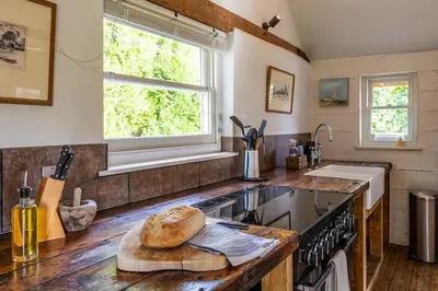 a kitchen with a counter with a loaf of bread on a cutting board at Belchamp Hall Mill in Belchamp Otten