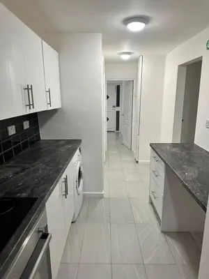 a kitchen with white cabinets and black counter tops at Basildon Everlight Villa in Basildon